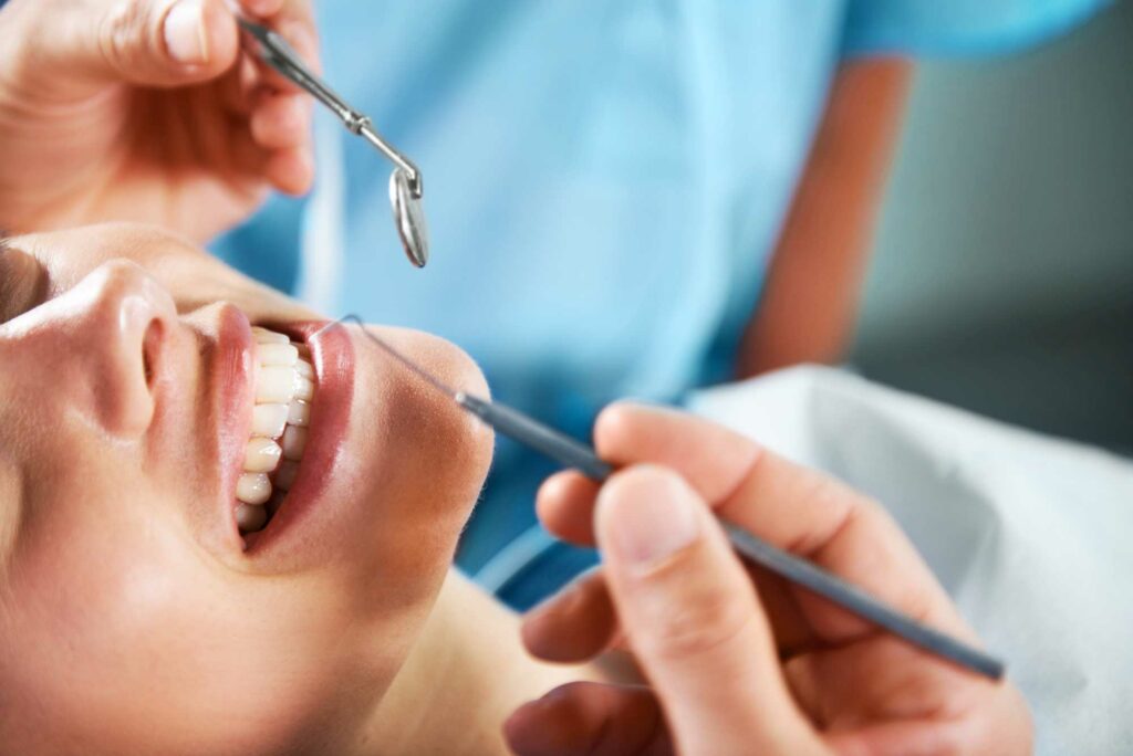 smiling woman with dental tools near her teeth